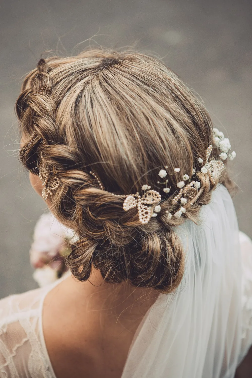 A bride with a braided crown hairstyle and long veil, seen from behind