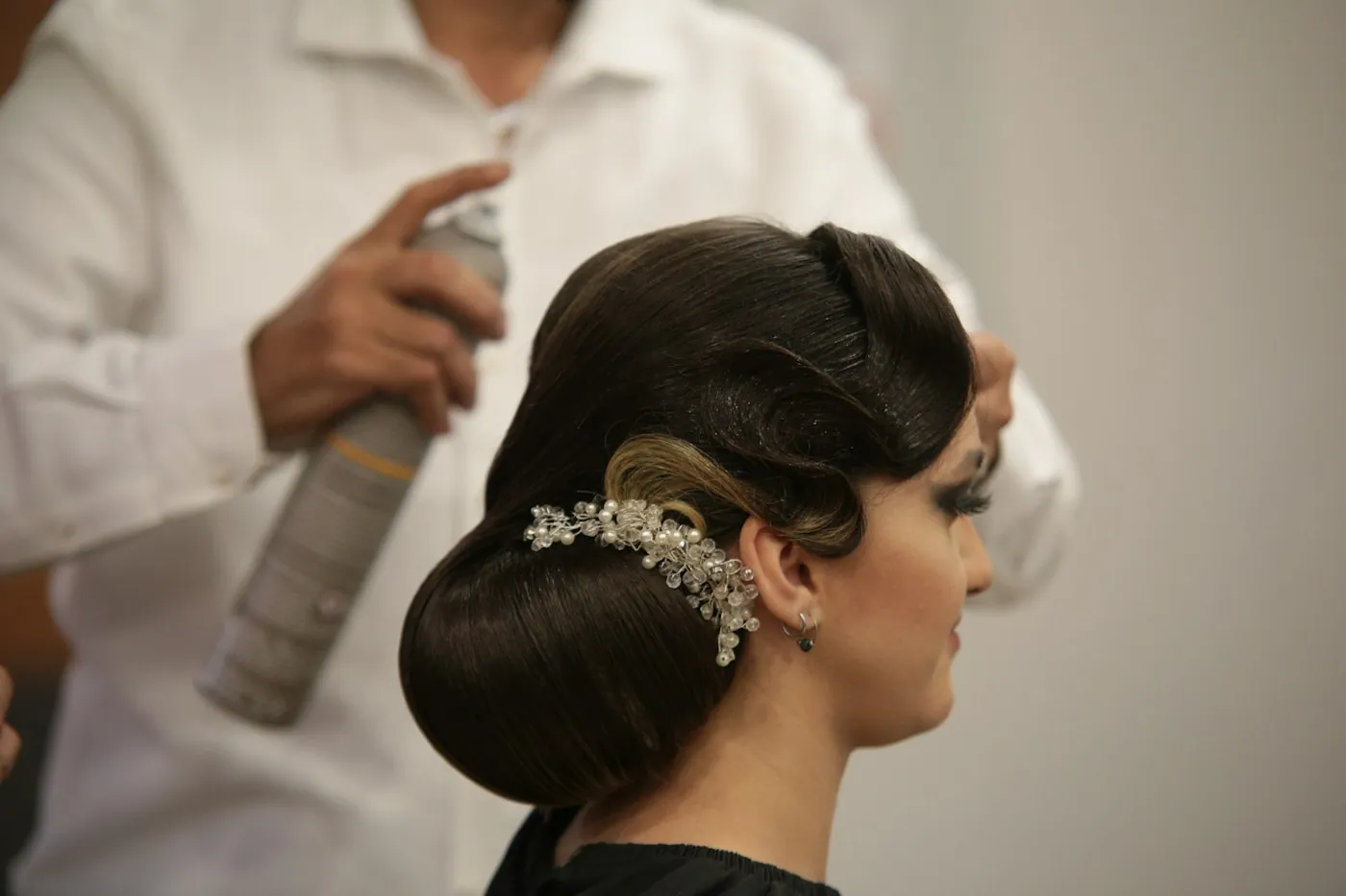A sculpted vintage-style updo with a jeweled comb being set with hairspray